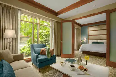 Wood-and-frosted French doors are open to reveal the luxurious living quarters in The Lodge suites with a king bed and soaking tub